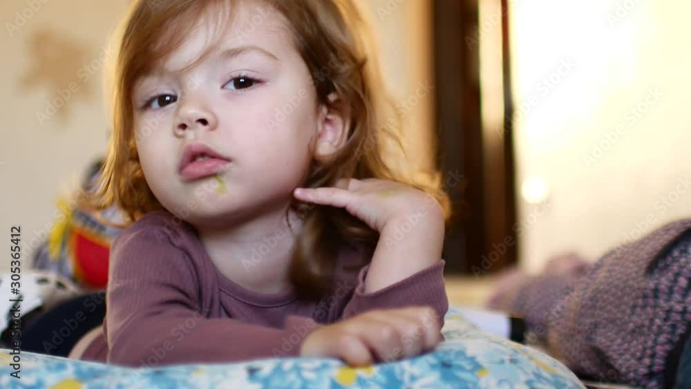Little sleepy girl. The child lies on the bed and struggles with sleep Little sleepy girl. The child lies on the bed and struggles with sleep