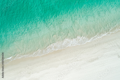 Aerial drone view of sandy white beach in summer with brilliant blue turquoise waters