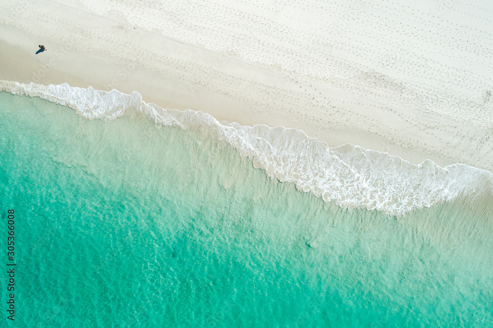 Aerial drone view of sandy white beach in summer with brilliant blue turquoise waters