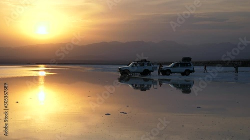 Wide angle view of vehicles out on the Danakil Depression salt flats during an amazing sunset
