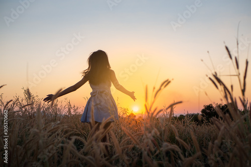 Trendy girl in stylish summer dress feeling free in the field with flowers in sunshine,enjoying nature, Beautiful Teenage Model in the Spring Field, Sun Light.