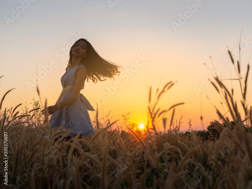 Trendy girl in stylish summer dress feeling free in the field with flowers in sunshine,enjoying nature, Beautiful Teenage Model in the Spring Field, Sun Light.