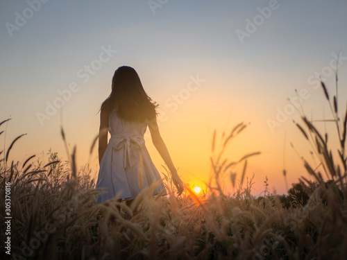 Trendy girl in stylish summer dress feeling free in the field with flowers in sunshine,enjoying nature, Beautiful Teenage Model in the Spring Field, Sun Light.