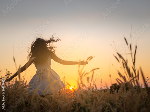 Trendy girl in stylish summer dress feeling free in the field with flowers in sunshine,enjoying nature, Beautiful Teenage Model in the Spring Field, Sun Light.