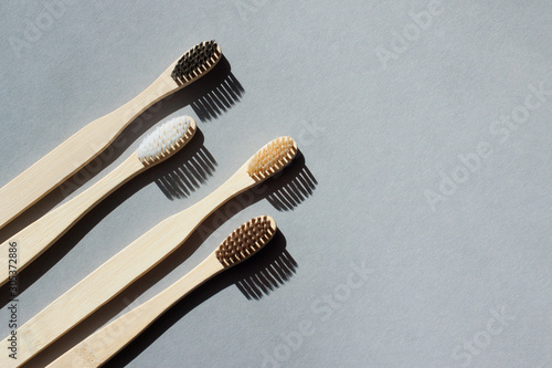 Four eco-friendly bamboo toothbrushes on a minimalistic gray background. Copy space. Zero waste concept  plastic-free  organic  eco-friendly shopping