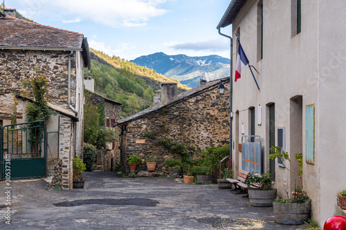 Rustic street in the medieval village of Evol in the French Pyrenees with a French flag hanging from a building