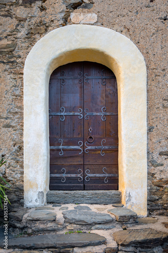 Medieval brown wooden door of a rustic stone building