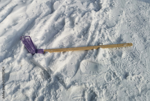 children's wooden hockey stick lies on white snow