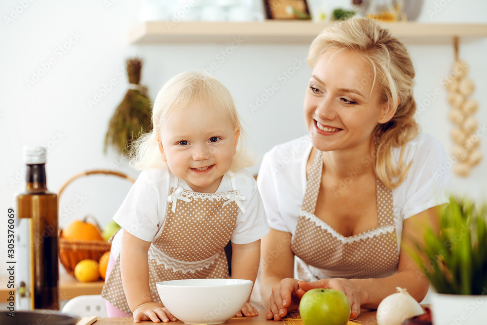 Happy mother and little daughter cooking in kitchen. Spending time all together, family fun concept Happy mother and little daughter cooking in kitchen. Spending time all together, family fun concept