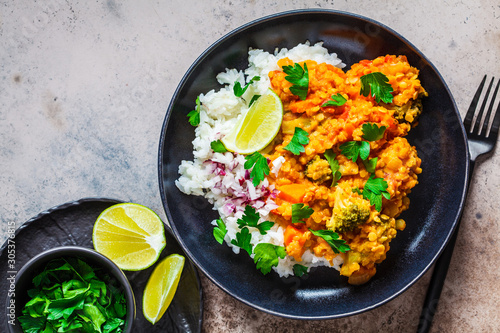 Vegetarian lentil curry with rice in black plate, top view. Healthy vegan food concept.