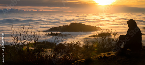 Frau sitzt oberhalb der Wolkendecke bei Sonnenuntergang im MÃ¼hlviertel bei St.Thomas am Blasenstein photo