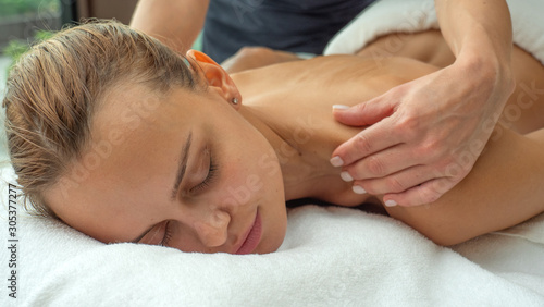 Close up of an young woman is receiving a back massage and spa treatment in a luxury wellness center.