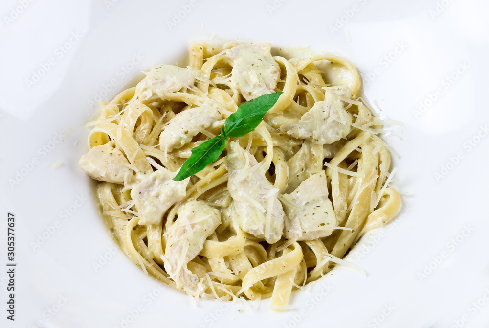 Italianate pasta with basil leaves and Parmesan cheese in a white plate on a wooden background
