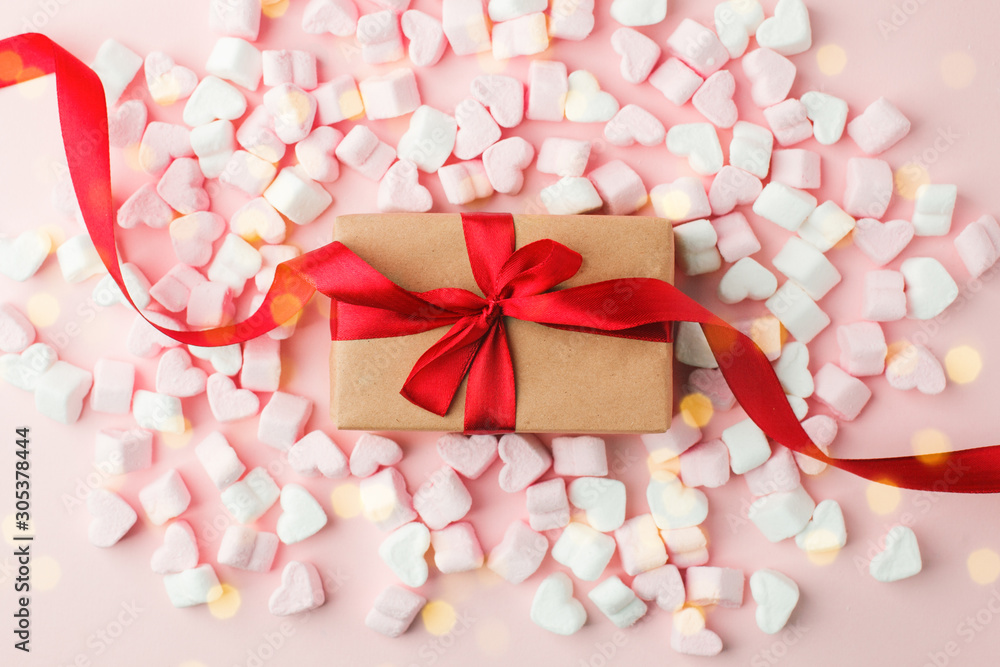 Gift box with ribbon and sweet candy marshmallow hearts on wpink table. Beautiful Valentines mother woman day background. Romantic mood. Flat lay, copy space Gift box with ribbon and sweet candy marshmallow hearts on wpink table. Beautiful Valentines mother woman day background. Romantic mood. Flat lay, copy space