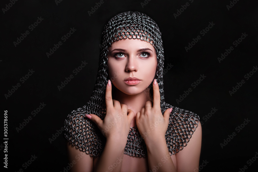 Portrait of a beautiful, young girl in a chainmail hood on a black background. Model with clean skin. Portrait of a beautiful, young girl in a chainmail hood on a black background. Model with clean skin.