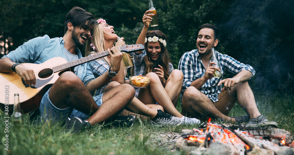 Obraz premium Happy friends playing music and enjoying bonfire