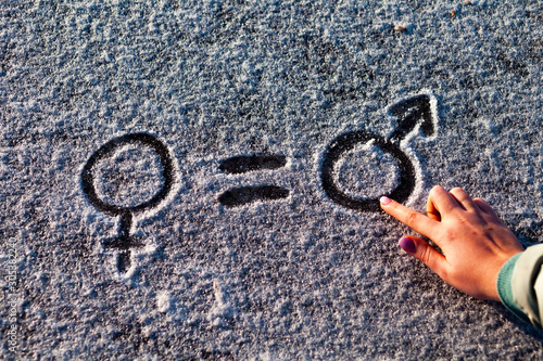 The symbols of gender in the snow. Female hand draws on the snow © Larisa