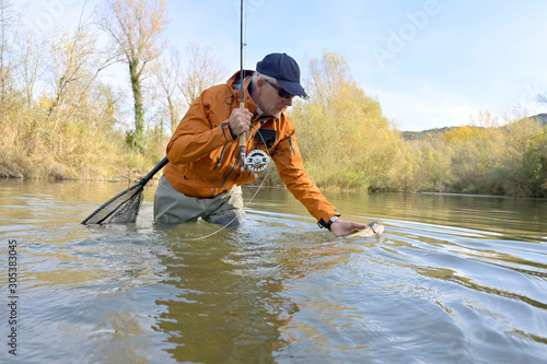 capture of a rainbow trout by a fly fisherman in autumn