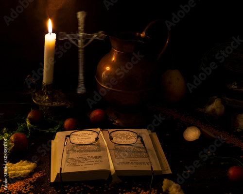 Prayer on wood table  candle and cross. The concept of waiting for Christmas. 11 22 2019. Montenegro. Mountain house interior.