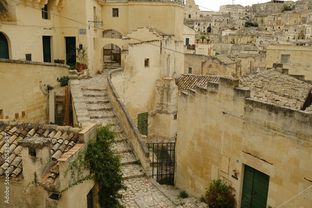 Stairway in a street of the ancient city of Matera. Beige stone paving and houses in tuff blocks.