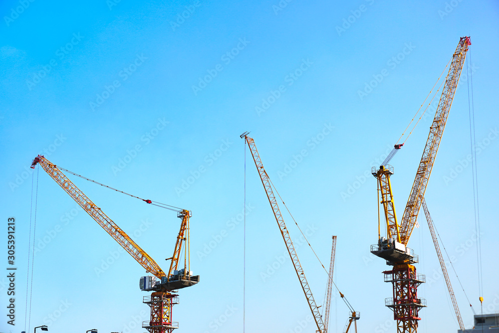 Two cranes are working at construction area with blue sky background