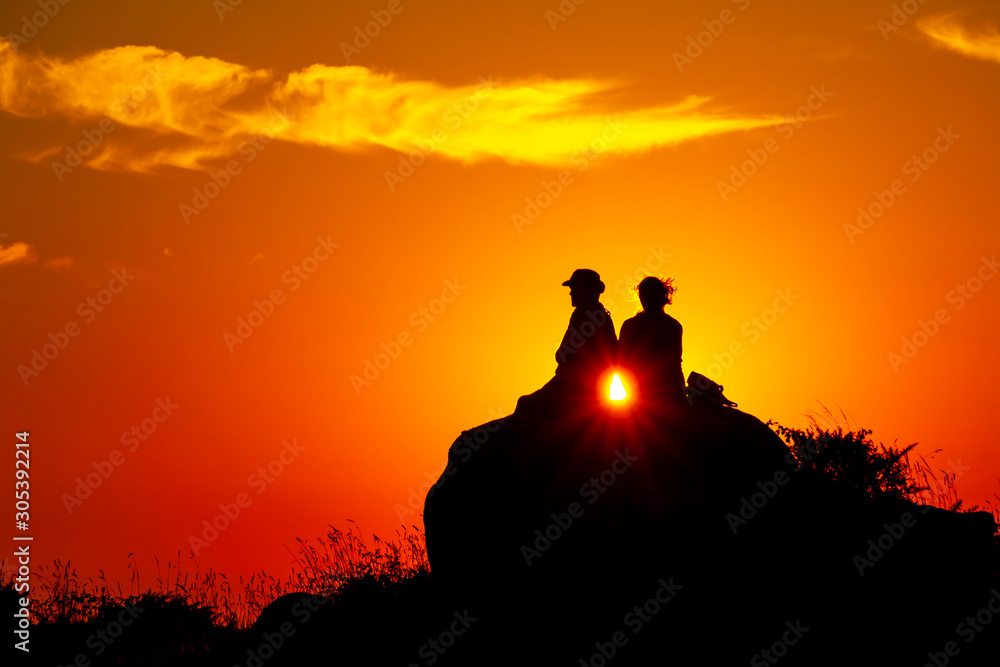 Silhouette of a romance couple looking at  the sunset on an orange sky