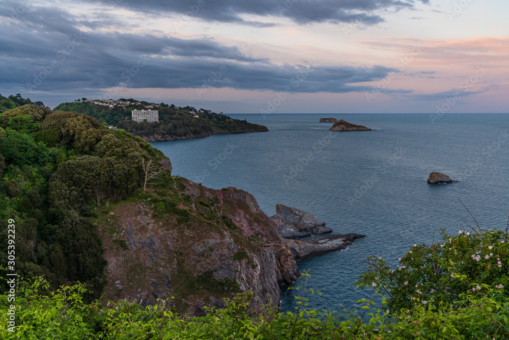 Evening light over Daddyhole Cove, with a view over the cliffs, the sea and Thatcher's Rock in Torquay, Torbay, England, UK