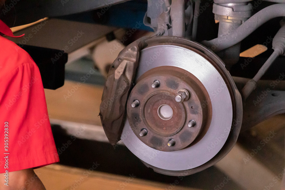 The mechanic is cleaning the front wheel brake set of the car before changing to a new wheel. The mechanic is cleaning the front wheel brake set of the car before changing to a new wheel.