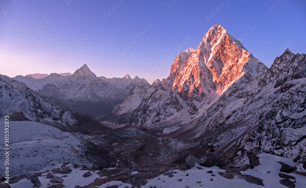 Majestic mountain peaks Cholatse (6501 m) and Ama Dablam (6814 m) at sunrise in Nepal, Himalayas; cloudless sky, the first rays of the sun, the beginning of a perfect day