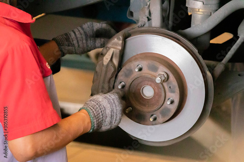 The mechanic is cleaning the front wheel brake set of the car before changing to a new wheel.