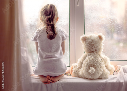 Little cute girl is looking out the window