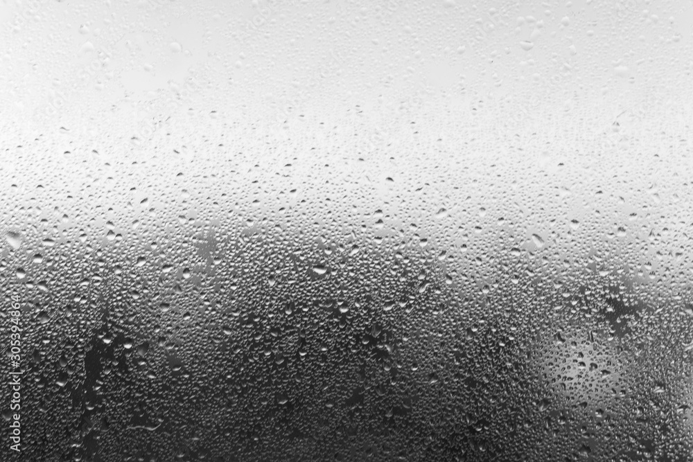 Condensation drop on glass, close-up. Black and white defocused backdrop