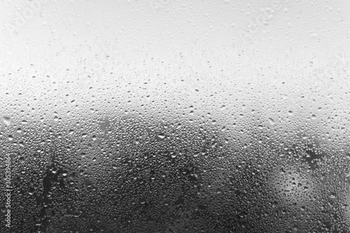 Condensation drop on glass, close-up. Black and white defocused backdrop