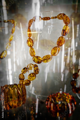 Amber neklace and bracelet on a glass shelf.