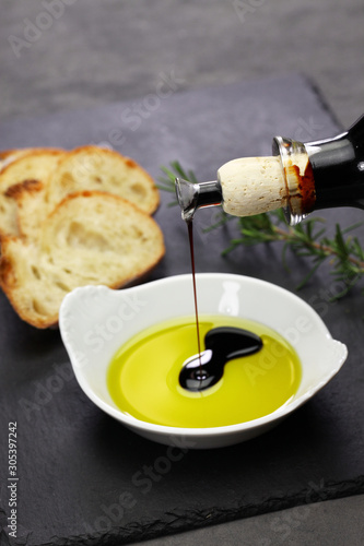 Vászonkép pouring balsamic vinegar into olive oil, making dipping sauce