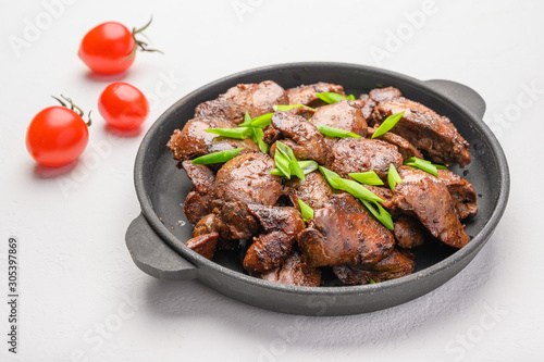 Homemade chicken liver fried with soy sauce, tomatoes, onions and spices on light background
