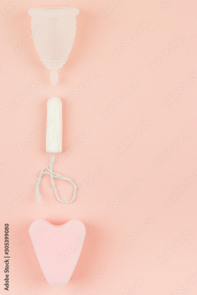 Close up of menstrual cup, tampon and sponge on pink