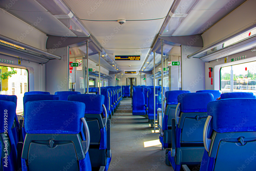 Interior of the train for long and short distance. Interior view of a corridor inside passenger trains with blue fabric seats railway train system. Empty vacant passenger car inside the train Interior of the train for long and short distance. Interior view of a corridor inside passenger trains with blue fabric seats railway train system. Empty vacant passenger car inside the train