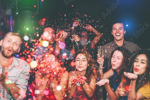Happy friends doing party throwing confetti in nightclub - Group young people having fun celebrating new year holidays together in disco club - Youth culture entertainment lifestyle concept
