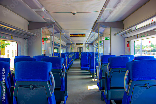 Interior of the train for long and short distance. Interior view of a corridor inside passenger trains with blue fabric seats railway train system. Empty vacant passenger car inside the train