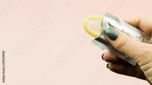 Woman's hand holding opened condom in package