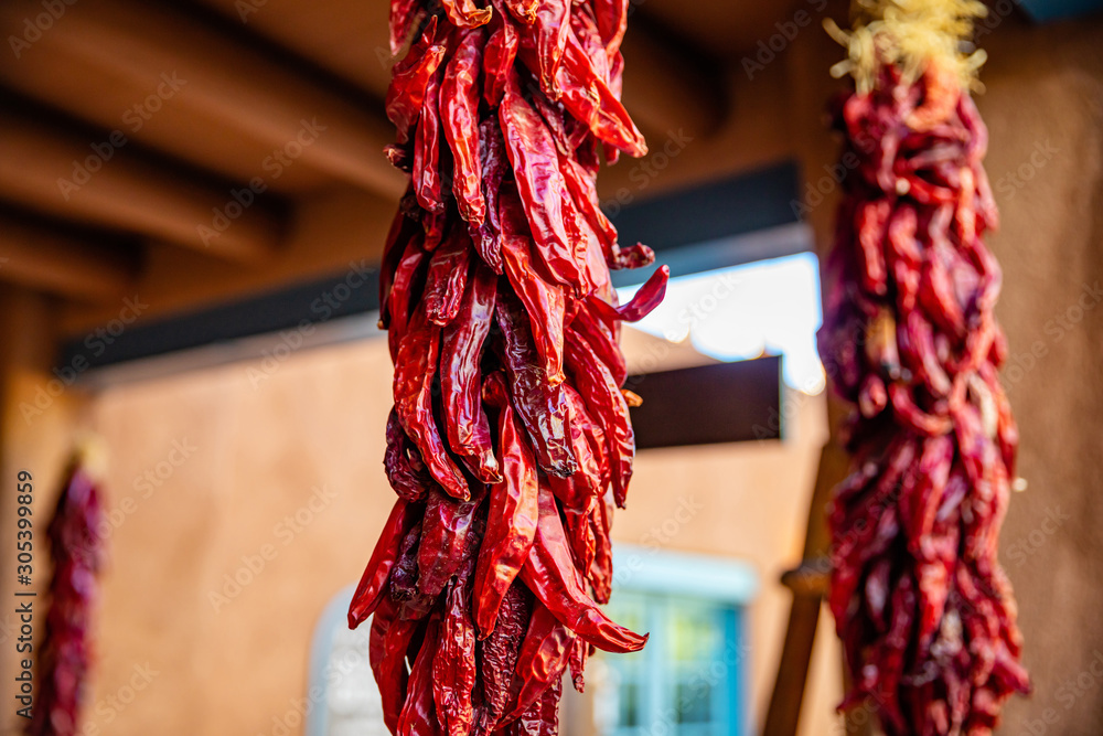 Fototapeta premium Czerwona papryka chili suszone wiszące na wejściu do tradycyjnego budynku, Santa Fe w Nowym Meksyku