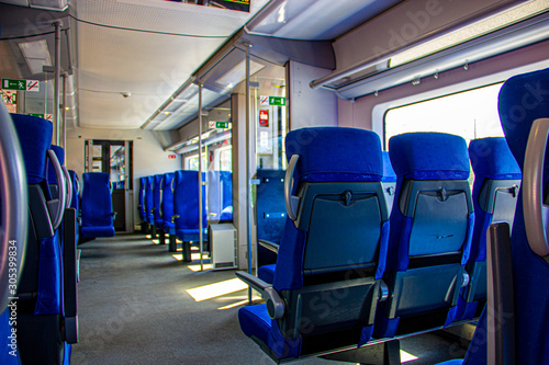 Interior of the train for long and short distance. Interior view of a corridor inside passenger trains with blue fabric seats  railway train system. Empty vacant passenger car inside the train
