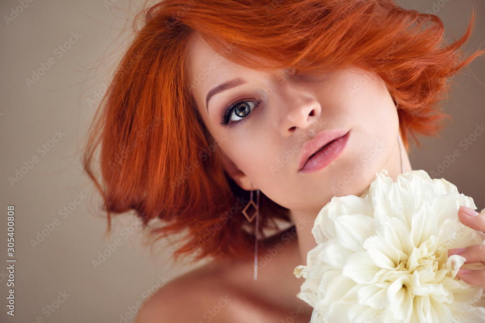 Portrait of young beautiful redhaired woman with white flower