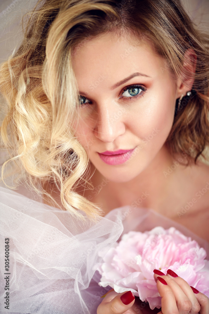 Portrait of a young blonde woman with pink flower