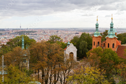 City views Prague autumn. Green foliage in the foreground. Tiled roofs. Petrshin. Church