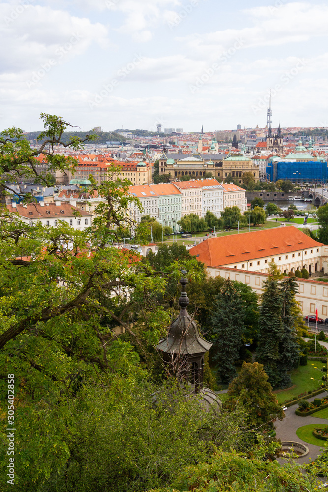 City views Prague autumn. Green foliage in the foreground. Tiled roofs