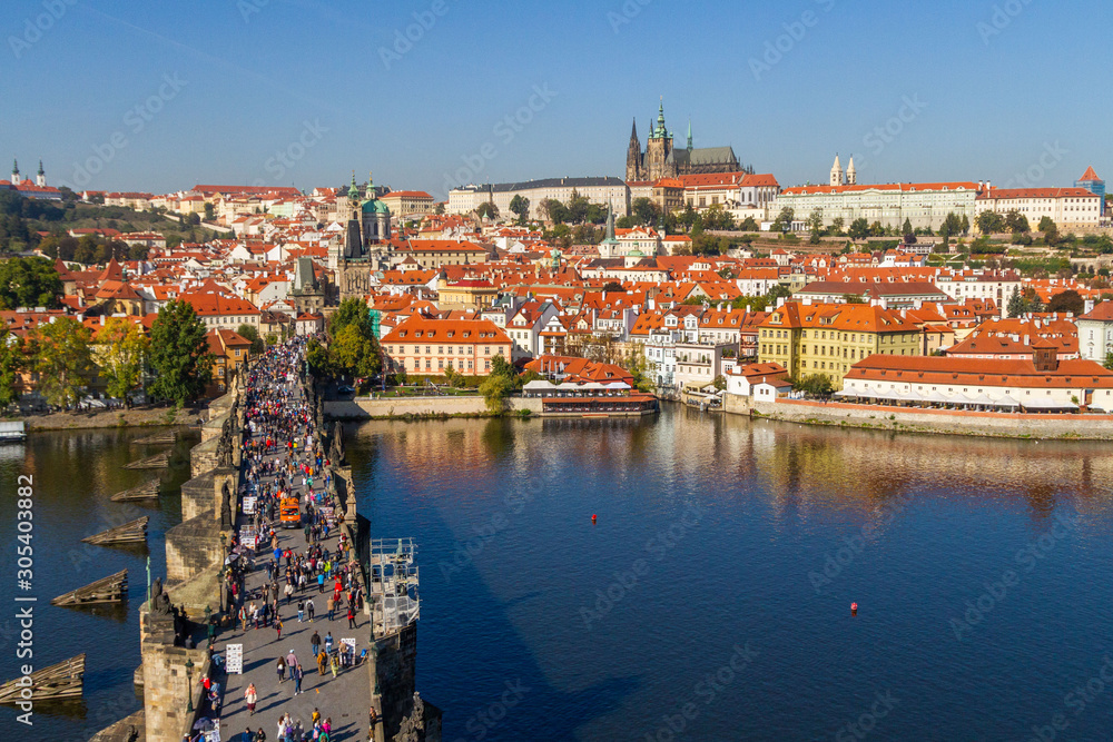 City views Prague autumn. Tiled roofs. The Charles Bridge. Vlatva river. People and Harvesting Equipment. View from above.