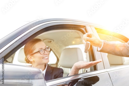Cropped hand of woman giving car key to smiling businesswoman