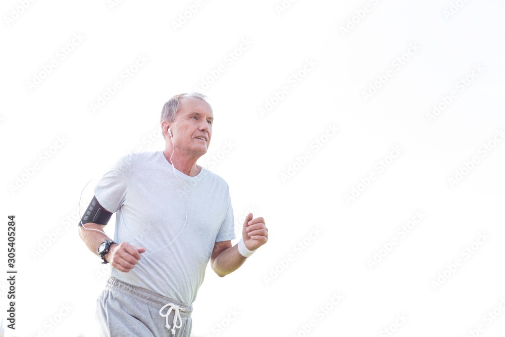 Dedicated senior man jogging against sky Dedicated senior man jogging against sky